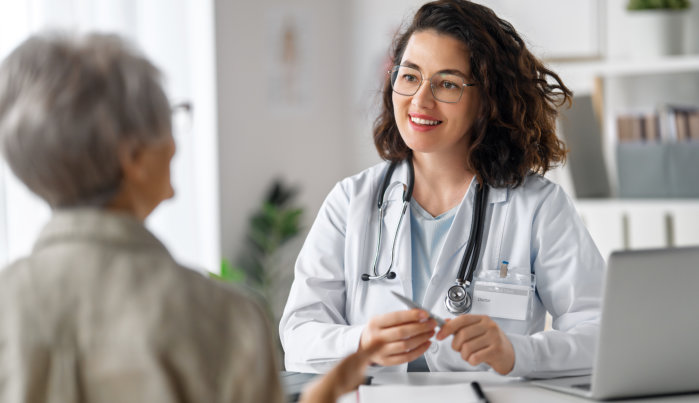 a female doctor listening to elderly woman